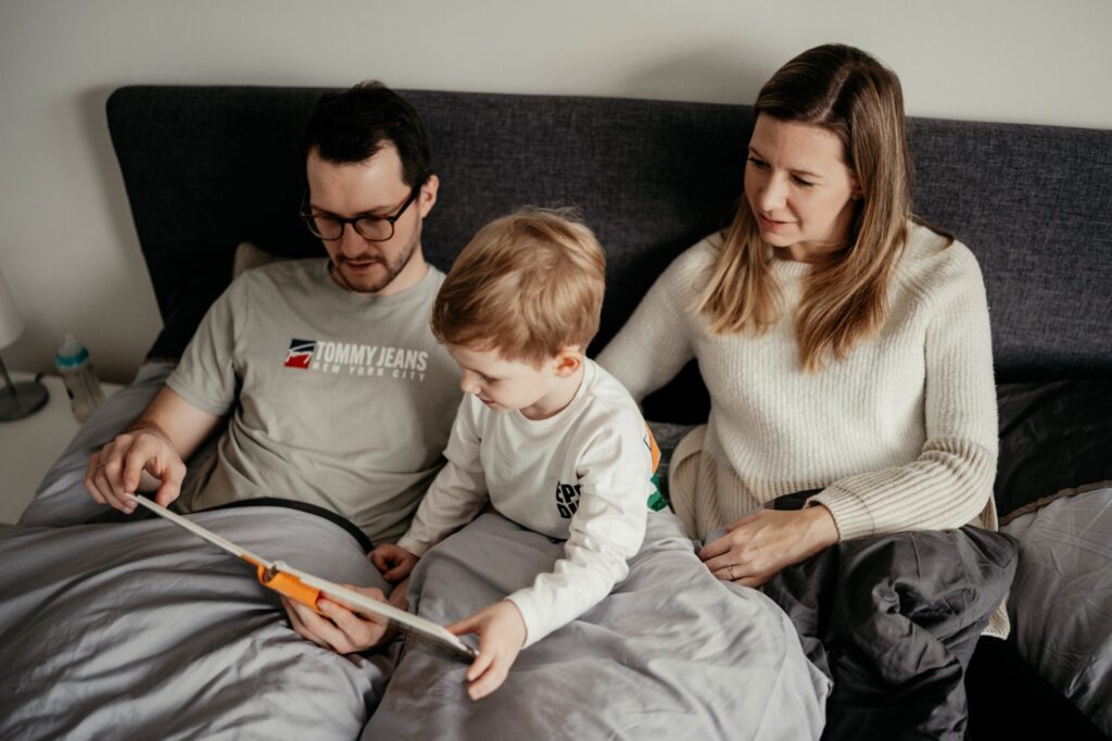 Mama, Papa und Sohn lesen gemeinsam ein Buch im Bett
