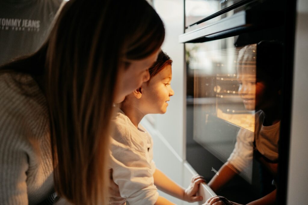 Mama und Sohn schauen gespannt in den Backofen in dem die selbstgemachten Plätzchen backen