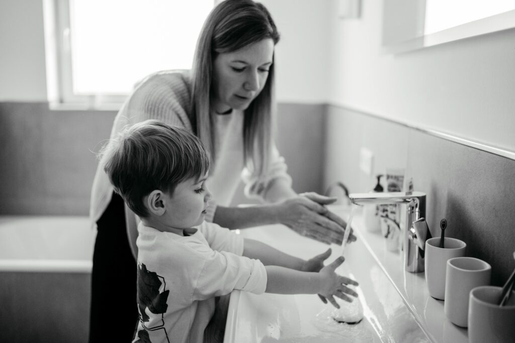 Mama und Sohn waschen sich gemeinsam die Hände im Badezimmer.